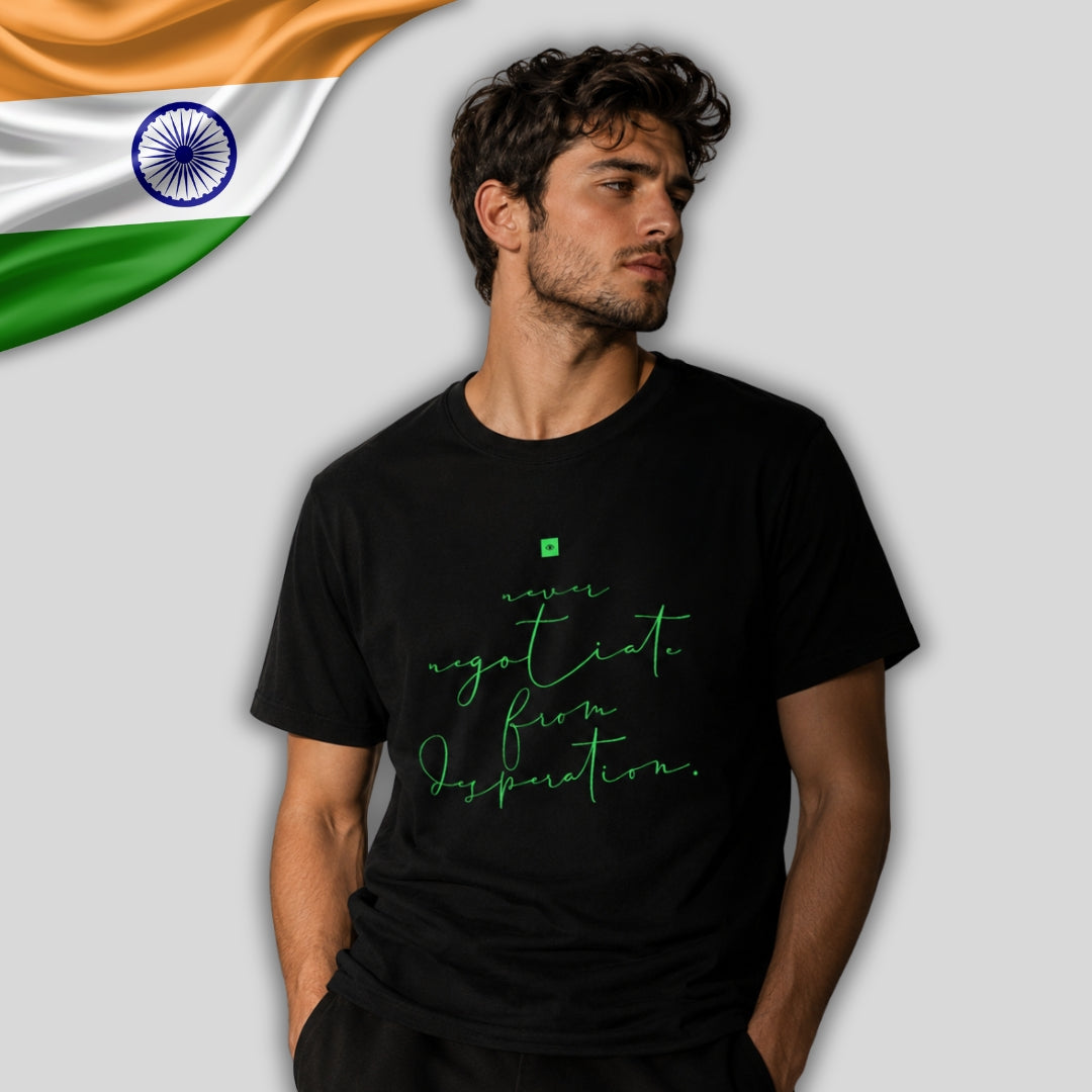 A man wearing a black t-shirt with green script text that reads 'negotiate from departure.' An Indian flag graphic is visible in the top-left corner against a light gray background.